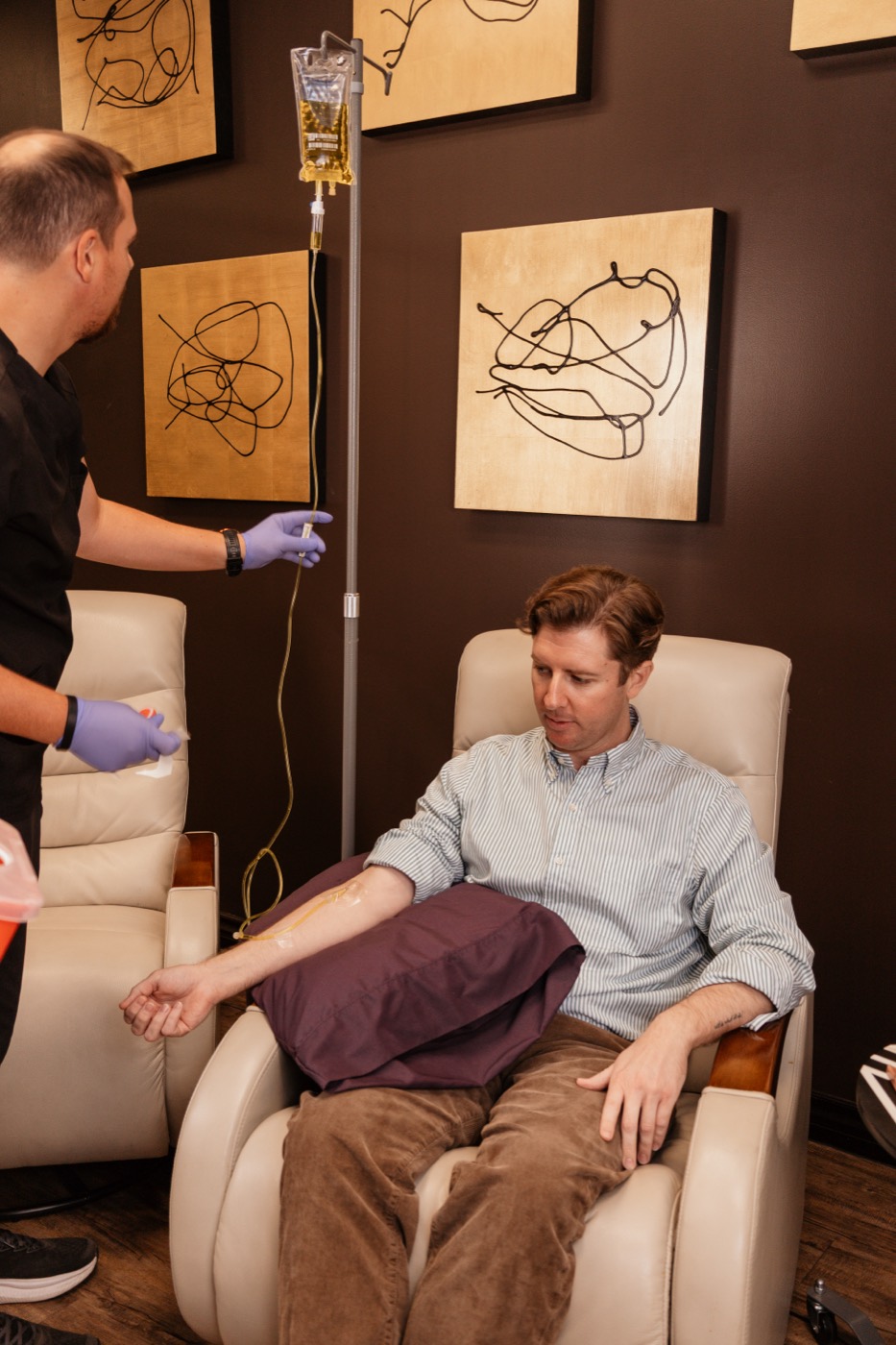 Dr. Kasey Nichols adjusting a vitamin IV drip for a patient in a recliner